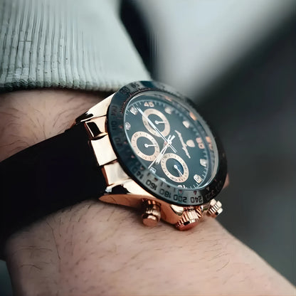 Luxury watch with rose gold case and black strap on wrist against a blurred background