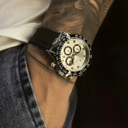 Close-up of a person wearing a black wristwatch with a detailed face, tattooed arm visible.