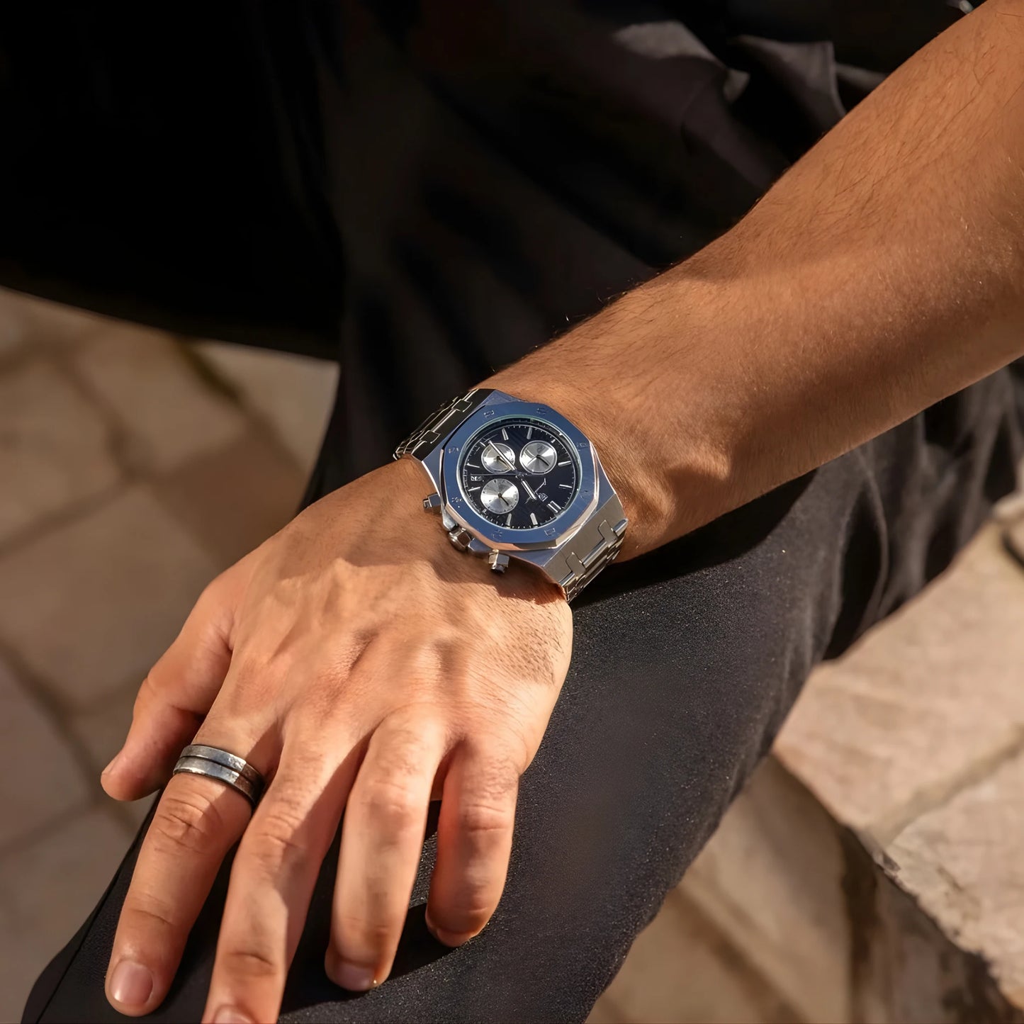 Person wearing a blue watch on a blurred outdoor background